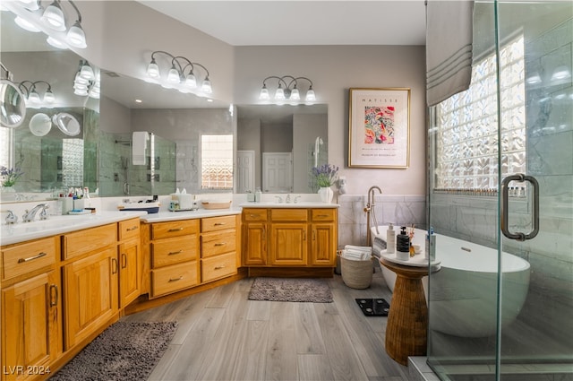 bathroom featuring a sink, wood finished floors, tile walls, a shower stall, and double vanity