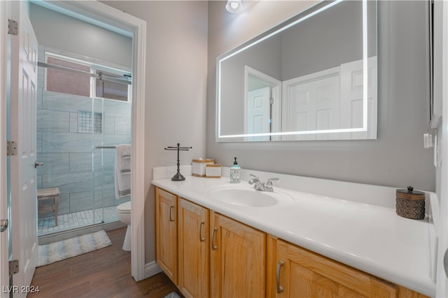 bathroom featuring vanity, toilet, wood finished floors, and a stall shower