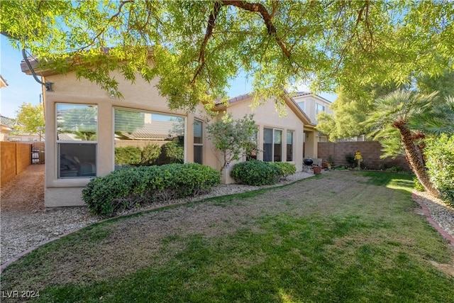 back of house with a yard, a fenced backyard, and stucco siding