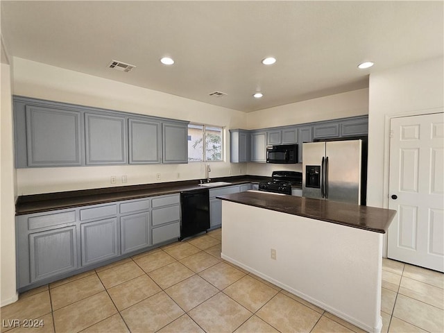 kitchen with gray cabinetry, light tile patterned flooring, black appliances, sink, and a kitchen island