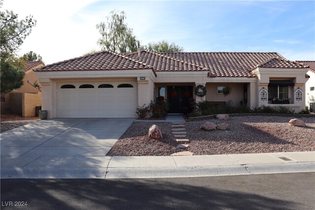 mediterranean / spanish house featuring stucco siding, driveway, an attached garage, and a tile roof