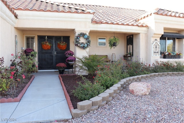 view of exterior entry with stucco siding and a tile roof