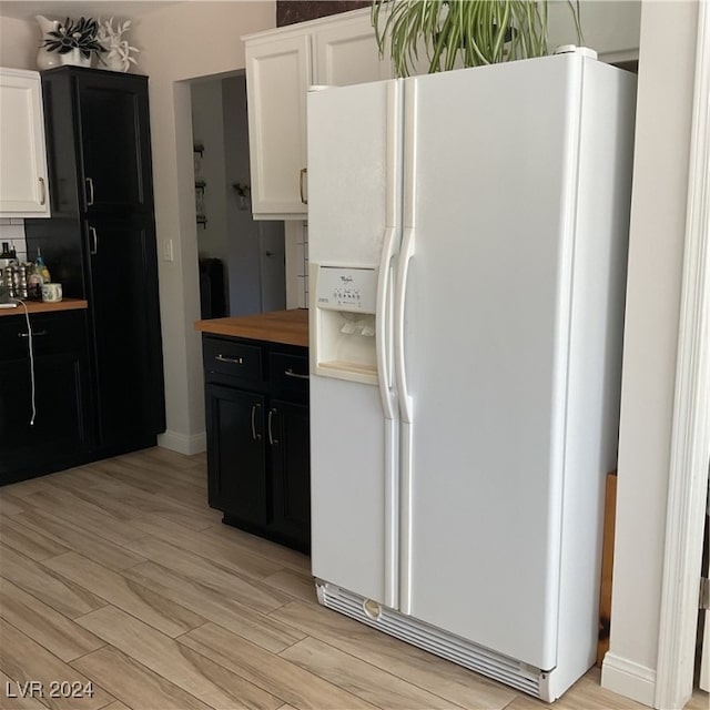 kitchen with white refrigerator with ice dispenser, white cabinets, light hardwood / wood-style flooring, and butcher block countertops