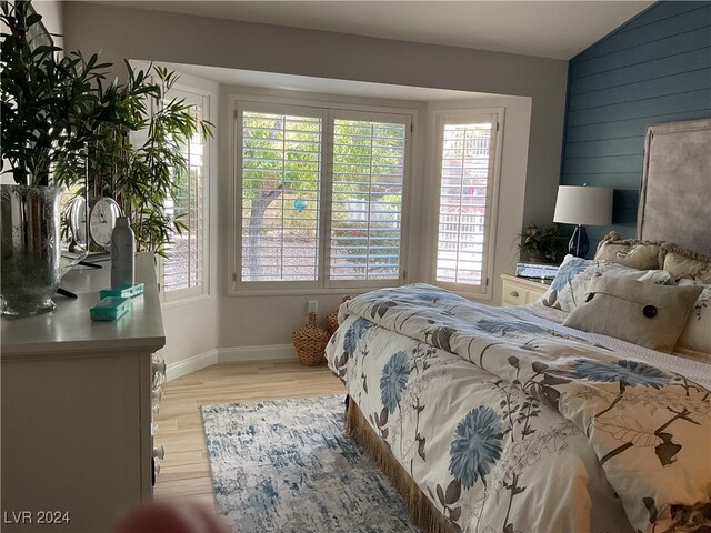 bedroom featuring lofted ceiling, light wood-type flooring, and wooden walls