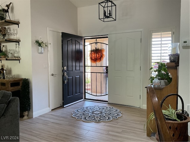 entryway with light hardwood / wood-style floors and an inviting chandelier