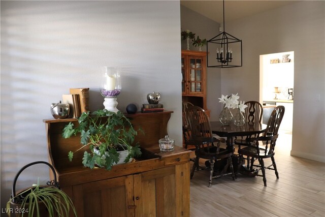 dining area with light wood-type flooring and an inviting chandelier