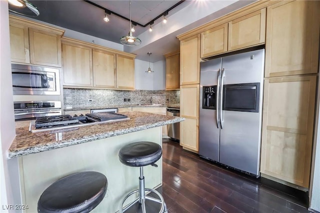 kitchen with light stone countertops, appliances with stainless steel finishes, a breakfast bar area, and hanging light fixtures