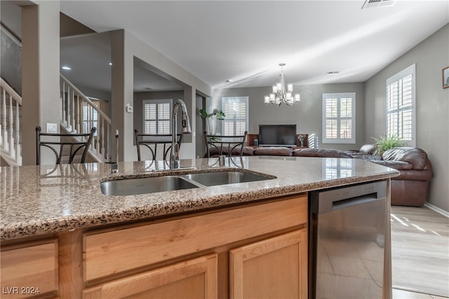 kitchen with dishwasher, a notable chandelier, sink, light stone countertops, and light hardwood / wood-style flooring