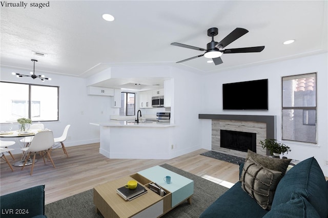 living room with a wealth of natural light, ceiling fan with notable chandelier, and light wood-type flooring