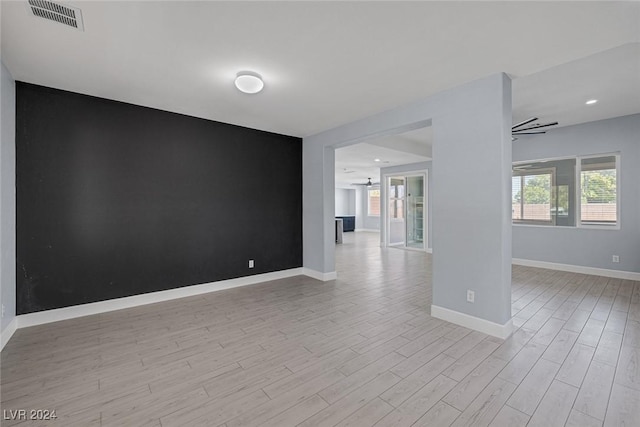 empty room with ceiling fan and light hardwood / wood-style floors