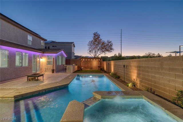 pool at dusk featuring an in ground hot tub and a patio area