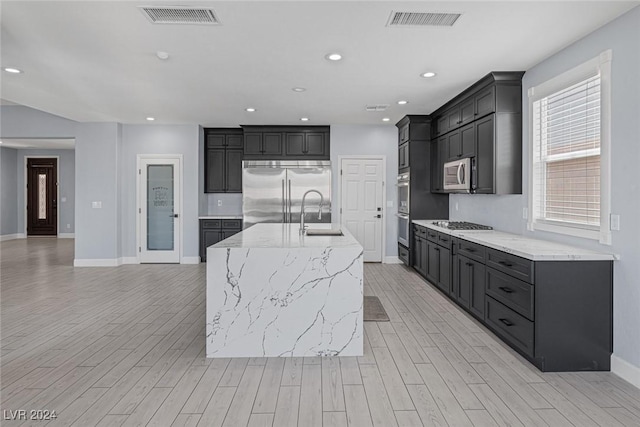 kitchen featuring sink, a center island with sink, light hardwood / wood-style floors, and appliances with stainless steel finishes