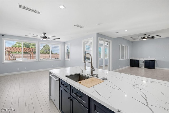 kitchen with dishwasher, light stone counters, ceiling fan, and sink