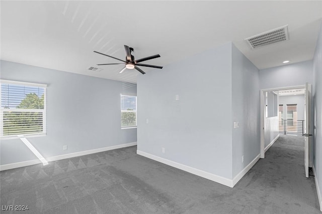 unfurnished room featuring dark carpet, plenty of natural light, and ceiling fan