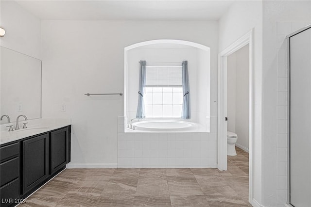 bathroom with vanity, toilet, and tiled tub