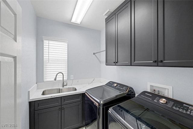 clothes washing area with cabinets, washing machine and clothes dryer, and sink