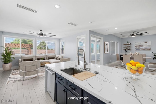 kitchen with sink, stainless steel dishwasher, ceiling fan, light hardwood / wood-style floors, and light stone counters