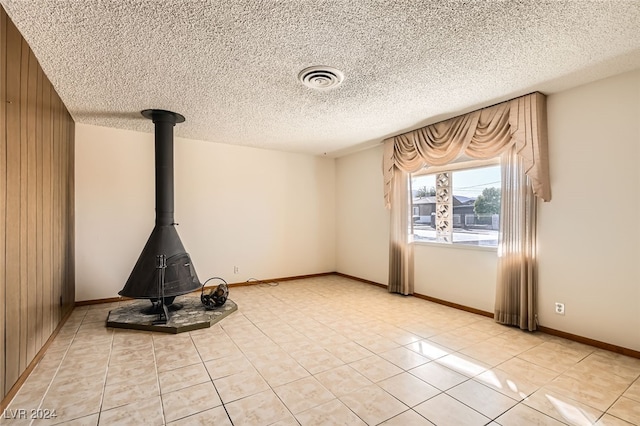 unfurnished living room with wood walls, light tile patterned flooring, and a textured ceiling