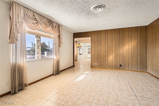 unfurnished room featuring a textured ceiling and wooden walls