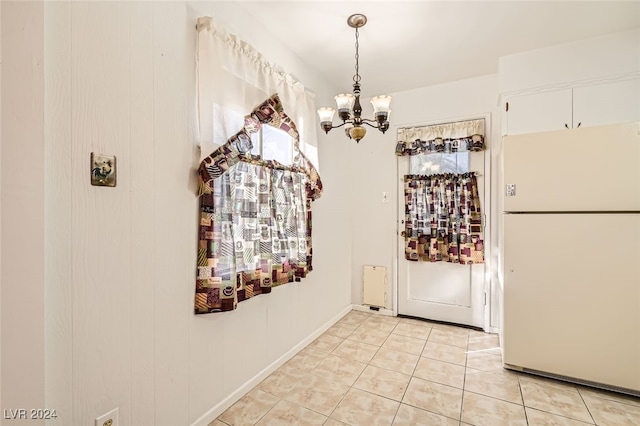 doorway with light tile patterned floors and a notable chandelier