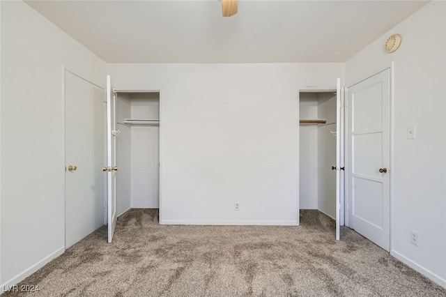 unfurnished bedroom with ceiling fan, light carpet, and two closets