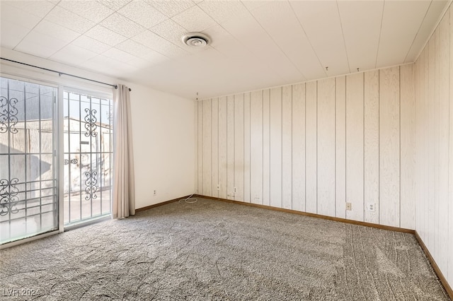 unfurnished room with carpet and wooden walls