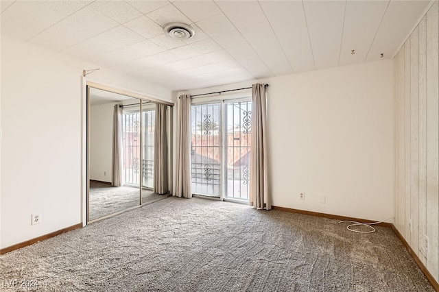 empty room featuring carpet floors and wood walls