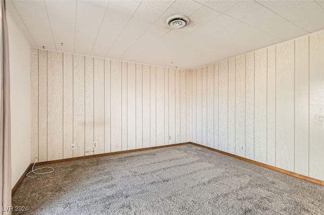 spare room with carpet and wood walls