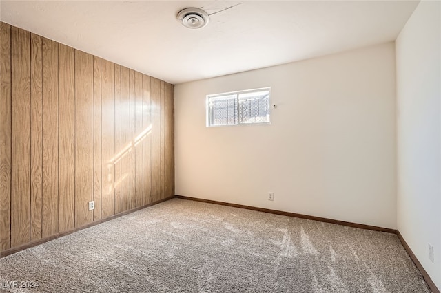 carpeted empty room featuring wood walls