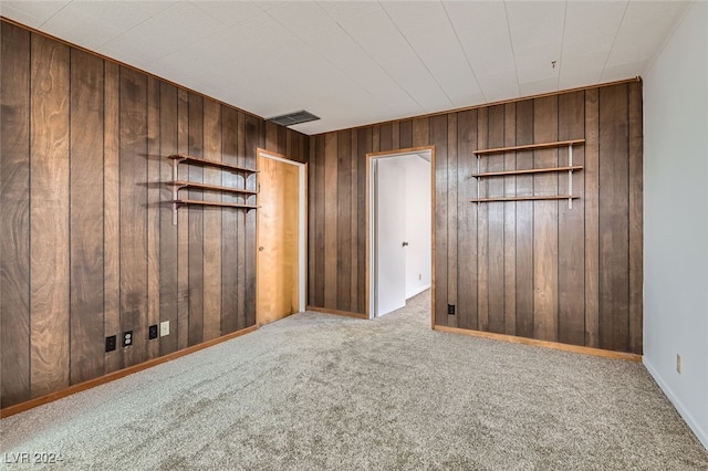 carpeted spare room with wood walls