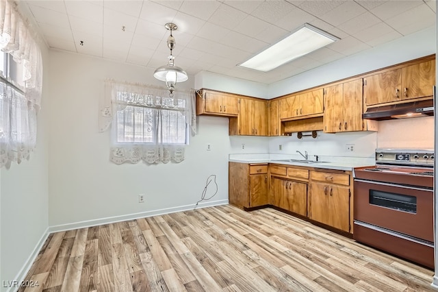 kitchen featuring pendant lighting, electric range oven, light hardwood / wood-style floors, and sink