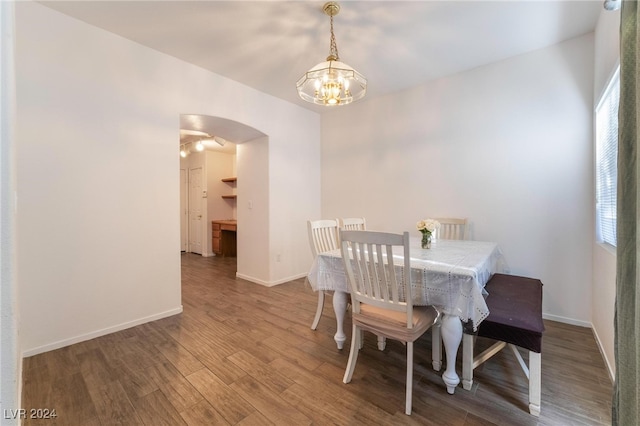 dining space featuring wood-type flooring, a healthy amount of sunlight, and a chandelier