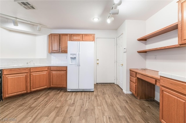 kitchen featuring tile counters, light wood-type flooring, white fridge with ice dispenser, and rail lighting