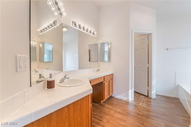 bathroom featuring hardwood / wood-style floors, vanity, and a tub to relax in