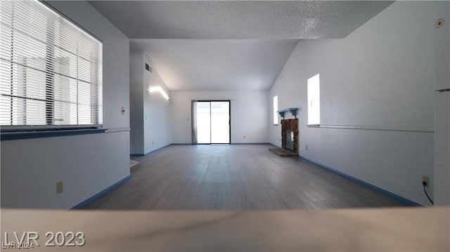 unfurnished living room with dark wood-type flooring, a textured ceiling, and lofted ceiling