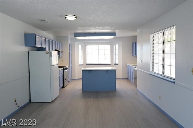 kitchen with white refrigerator, wood-type flooring, stainless steel range, and plenty of natural light