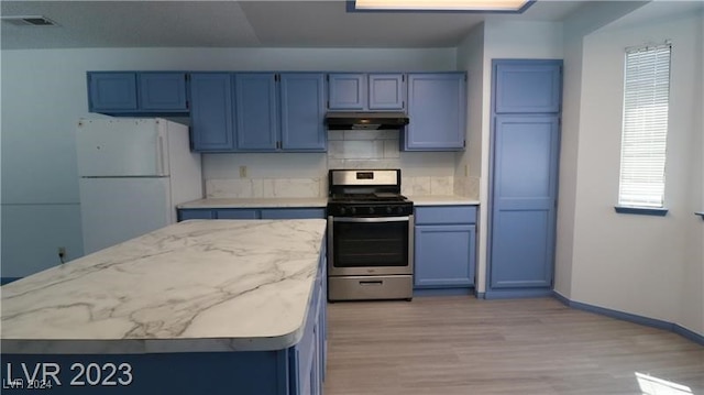 kitchen with tasteful backsplash, white fridge, blue cabinetry, stainless steel stove, and light hardwood / wood-style flooring