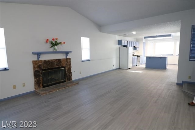 unfurnished living room featuring hardwood / wood-style flooring, a fireplace, lofted ceiling, and a healthy amount of sunlight