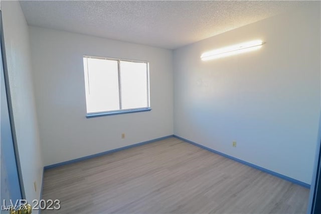 unfurnished room with a textured ceiling and light hardwood / wood-style flooring