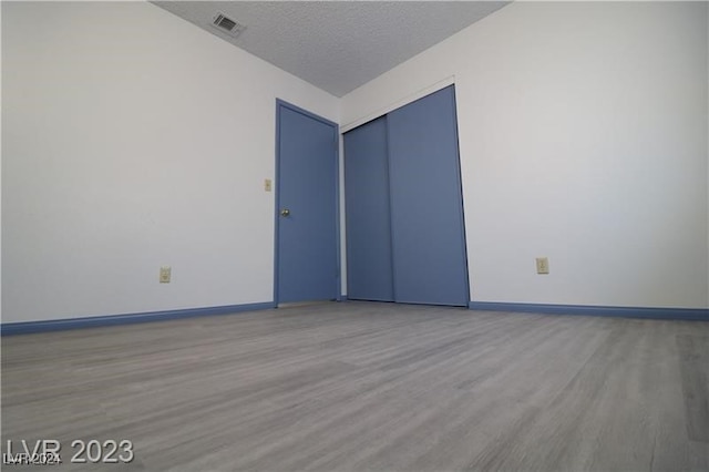 unfurnished room featuring a textured ceiling and light hardwood / wood-style flooring