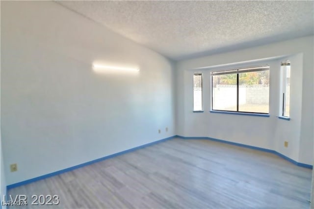 unfurnished room featuring wood-type flooring and a textured ceiling