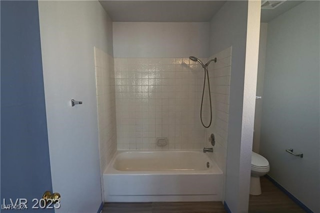 bathroom featuring tiled shower / bath, hardwood / wood-style flooring, and toilet