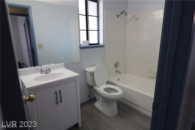 full bathroom with vanity, hardwood / wood-style flooring, toilet, and tiled shower / bath