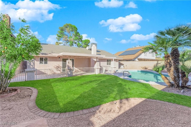 rear view of property with a yard and a fenced in pool