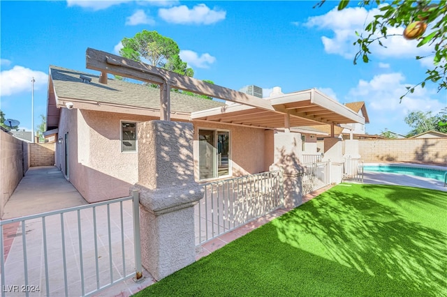 back of property featuring a yard and a fenced in pool