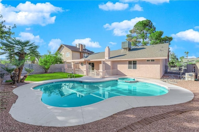 view of swimming pool featuring a yard, central AC unit, and an in ground hot tub