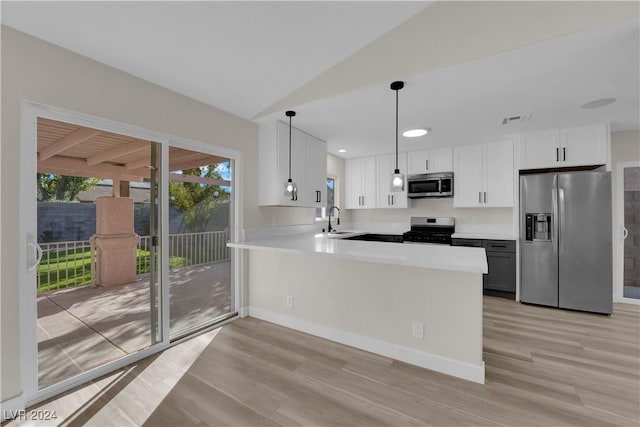 kitchen featuring kitchen peninsula, hanging light fixtures, stainless steel appliances, lofted ceiling, and white cabinets