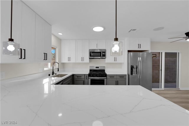 kitchen featuring appliances with stainless steel finishes, hanging light fixtures, gray cabinetry, sink, and white cabinetry