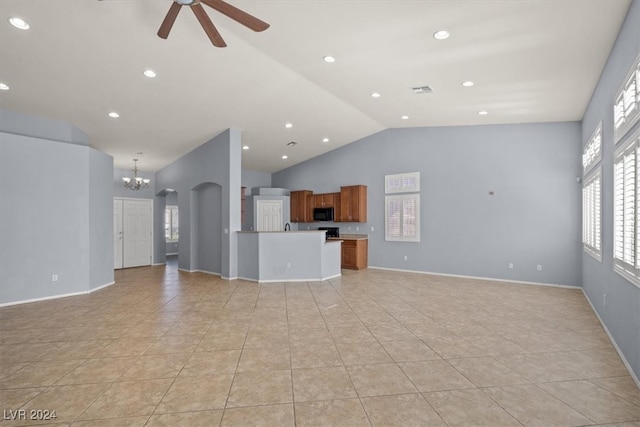 unfurnished living room with ceiling fan with notable chandelier, light tile patterned flooring, and vaulted ceiling