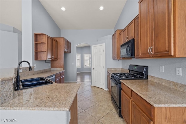 kitchen featuring black appliances, light stone counters, kitchen peninsula, sink, and lofted ceiling